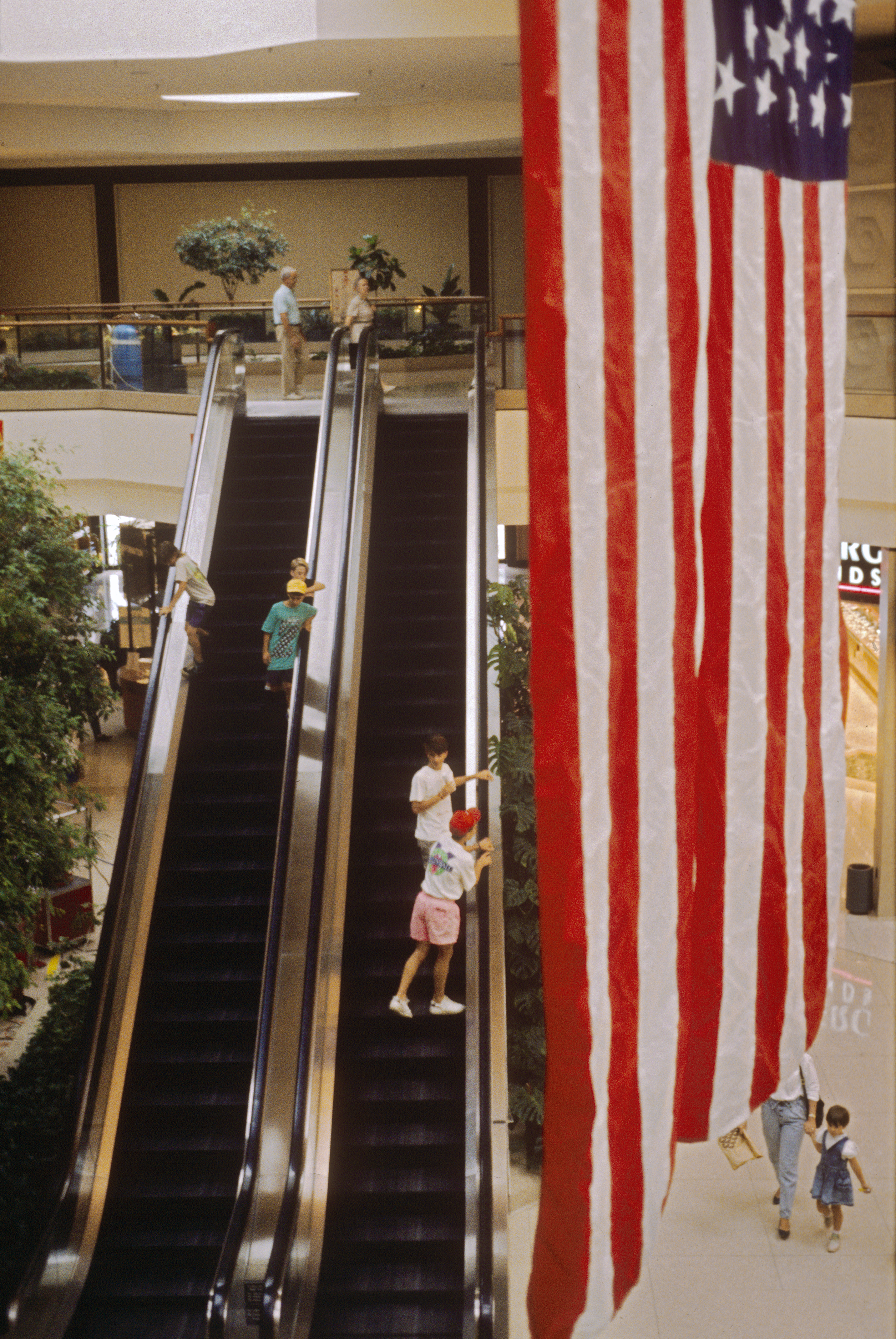 A mall escalator with the American flag in the foreground
